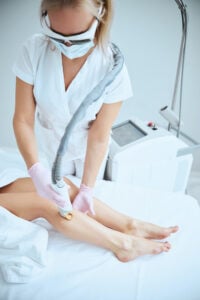 Épilation laser par des jambes par une professionnelle en salon d'esthétique