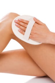 Exfoliation des jambes à l'aide d'une éponge exfolitante.