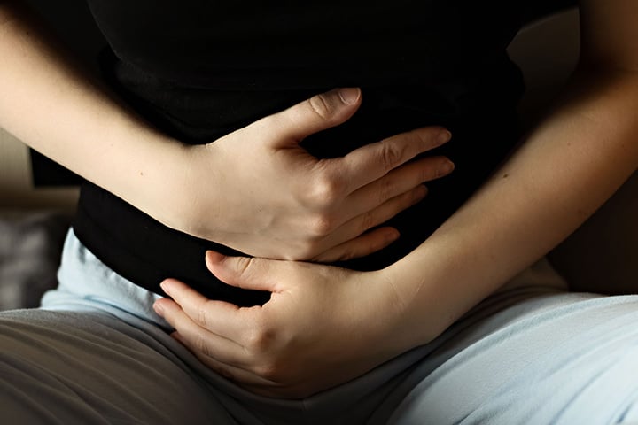 Une femme porte les mains à son abdomen