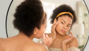 femme qui regarde la peau de son visage dans le miroir