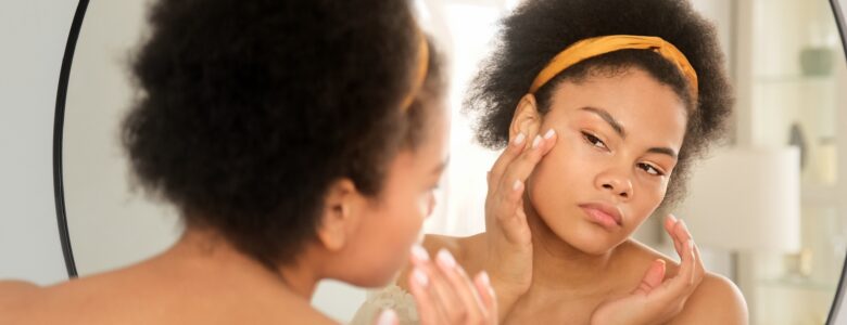 femme qui regarde la peau de son visage dans le miroir