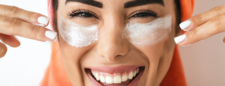 femme avec une serviette sur la tête et un masque dans le visage qui sourit.