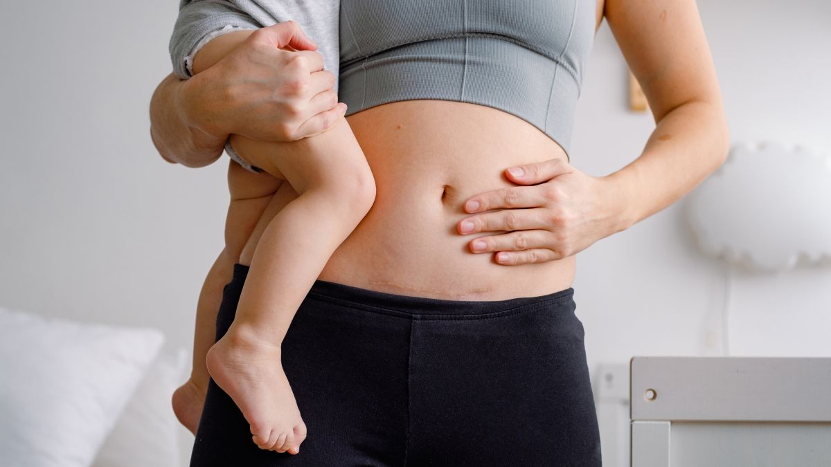 une femme tient son jeune enfant en se tenant le ventre